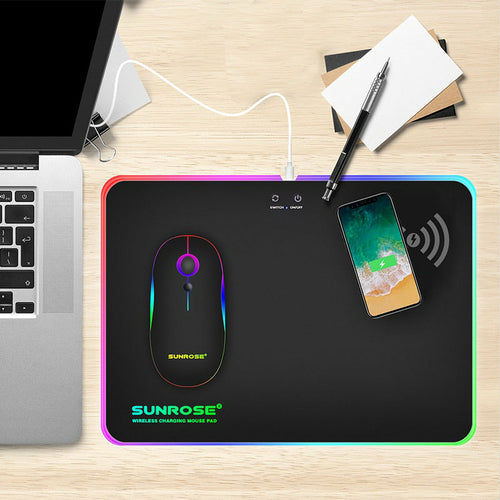 Wireless charging mouse pad on desk setup with phone charging on upper right corner